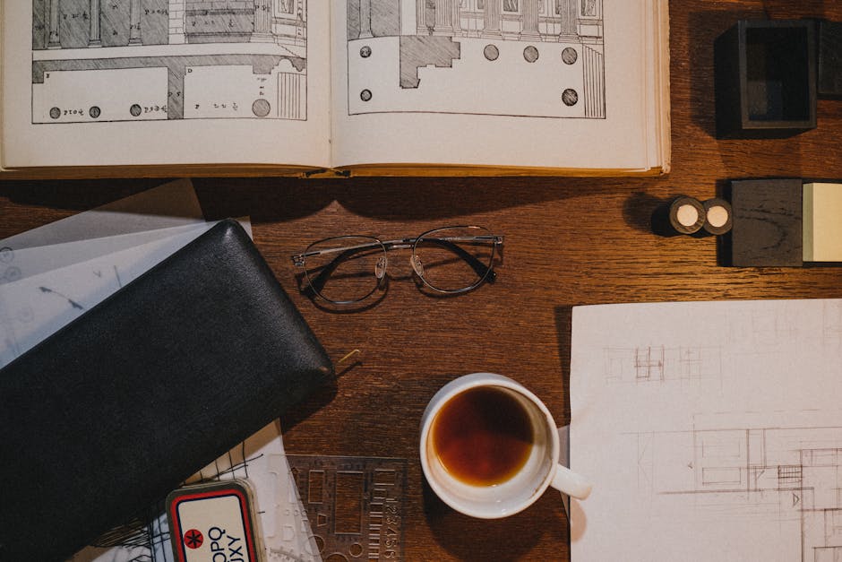 Flat lay of an architect's workspace with sketches, coffee, and drawing tools on a wooden desk.