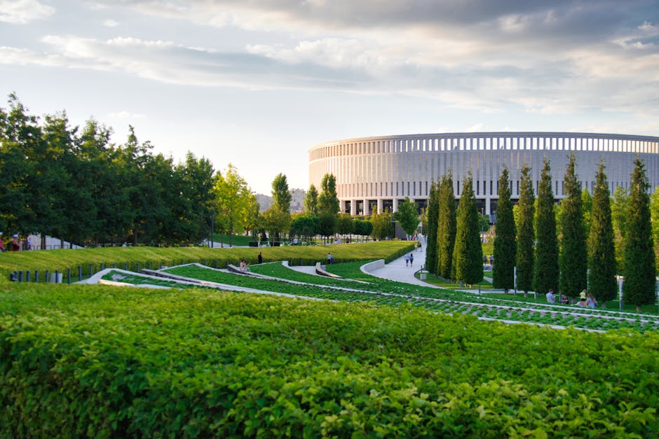 Vibrant park landscape featuring modern architecture, green trees, and lush gardens.